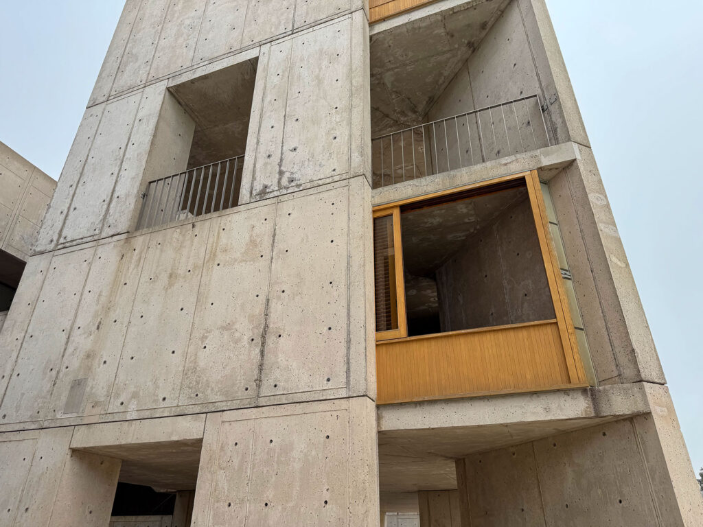 View looking up at a research tower at the Salk Institute. The teak sliding window is open so you can see inside the researcher's office.